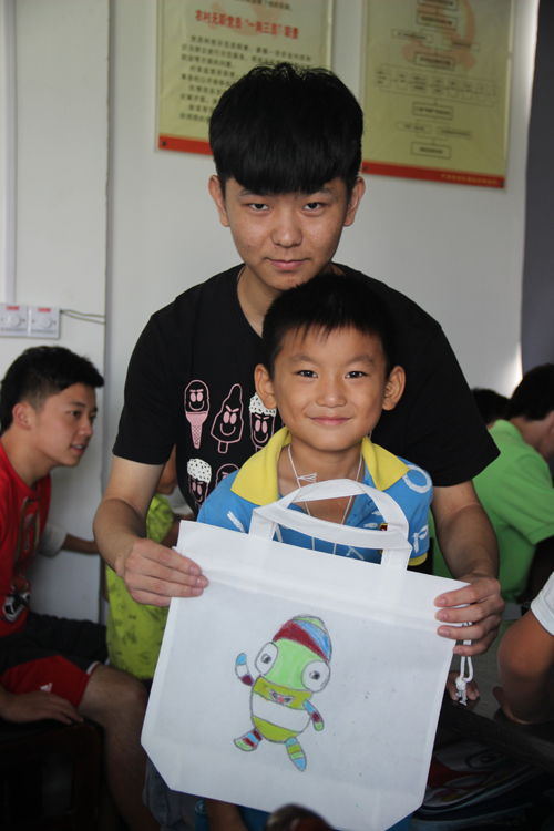 志愿者教留守儿童环保袋上画砳砳.JPG